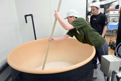 職人の指導を受けながら力を込めて櫂を動かす学生