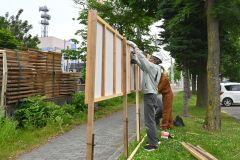ポスター掲示場をねじで固定する作業員ら