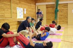 中学生に足を押さえてもらい、体力測定に臨む児童