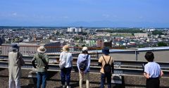 普段は立ち入ることができない帯広市役所屋上で日高山脈や市街地を眺める参加者(25日午前9時40分ごろ、塩原真撮影)