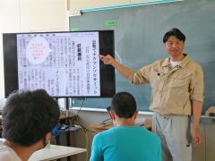 段ボールパネルの展示について説明する添田館長