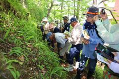 ルーペでコケを観察する受講者ら(左から4人目が乙幡さん)
