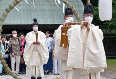 茅の輪をくぐる大野宮司(奥、塩原真撮影)