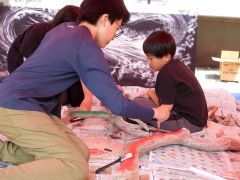 日幸さんの氣龍画の前で流木アートを作る参加者たち