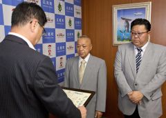 田中町長（手前）から感謝状を受け取る田中社長（中央）と、田中常務取締役