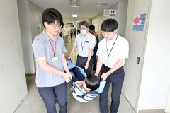 負傷者を運ぶ訓練を行う職員