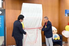 とかち帯広空港の２階ロビーで行われた除幕式の様子。左から、月森所長、飛岡会長