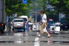 熱せられたアスファルトの上を歩く通行人（８日午前１１時半ごろ、市内西１南１０。金野和彦撮影