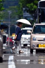 熱せられたアスファルトの上を日傘を差して歩く通行人（８日午前１１時２０分ごろ、市内西１南１０。金野和彦撮影