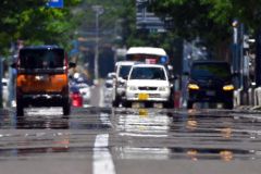 熱せられたアスファルトの上を走行する車（８日午前１１時半ごろ、市内西１南９。金野和彦撮影