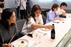日本酒のラベルを興味深そうに見つめるモニターツアー参加者（須貝拓也撮影）
