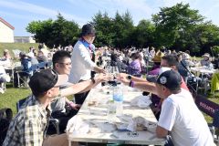 青空の下、十勝ワインで乾杯する参加者