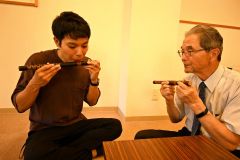 音更雅楽会の齊藤会長（右）から龍笛の音の出し方を教わる参加者（左）