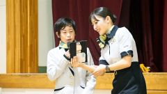客室乗務員から機内アナウンスの指導を受ける児童