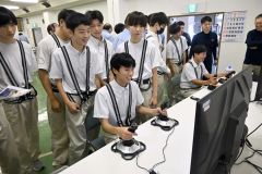 シミュレーターでバックホー操作を体験する生徒たち