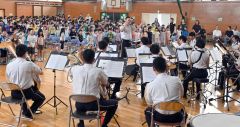 音楽隊の演奏に合わせて校歌を歌う児童ら