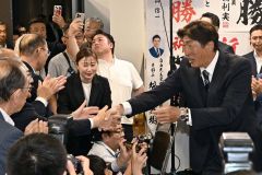 支援者の拍手に迎えられながら選対本部に入る岩本氏(21日午前2時35分、須貝拓也撮影)