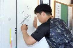 帯広の森平和球場の本部棟の壁にサインを書き込む澁谷純希投手