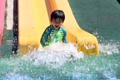 水を浴びながら滑り台を下りる子ども（２４日午前１０時１５分ごろ、芽室公園で。須貝拓也撮影）