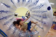帯広市児童会館の冷房の効いた室内で、回転遊具に乗り、笑顔の子どもたち（２４日午後３時）
