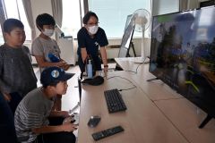 スクリーンでドローン操縦を体験する児童