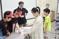 アレクサンダーさん(左から3人目)とロールプレイングで英語を学ぶ児童ら