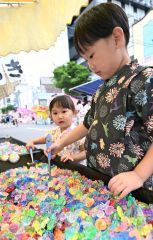 出店のアクセサリーすくいを楽しむ子ども（須貝拓也撮影）