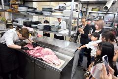肉をさばく岡田美佳料理長と見学する参加者