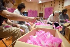 平らな形で美濃市から送られてきたこよりが付いた和紙を、花形に成形する参加者