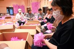 平らな形で美濃市から送られてきたこよりが付いた和紙を、花形に成形する参加者