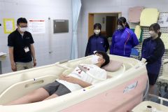 寝たきりになった人が使用する風呂を体験する生徒