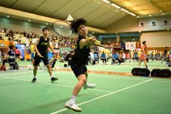 【男子個人戦ダブルス１回戦】第２ゲーム、帯大谷の若林辰樹（手前）がシャトルを打ち返す。左後方は櫻田琉晟（金野和彦撮影）