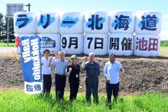 麦稈ロールで作った看板と成功させる会のメンバー