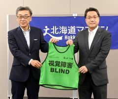 西山常務執行役員管理統括部長（右）から惣田副実行委員長にビブスが手渡された