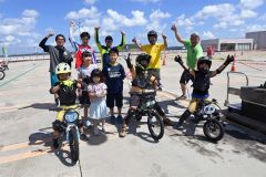 電動バイク体験後、スタッフらと記念撮影する子供たち(13日)