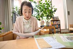 自身が制作した短歌を詠む舟橋さん。手前にある新聞切り抜きは、特攻隊員に対する思いを込めて少女時代に書き、入選した際のもの