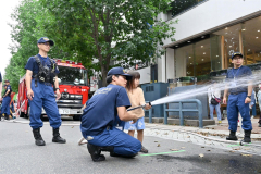 放水してパネルを倒す消防士体験に挑戦する子ども