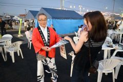 来場者にタオルとチラシを配る三浦会長