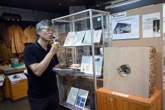 コンクリート壁に残る弾痕を説明する山本さん