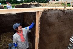 麦わらのブロックに土を塗り込み、土壁を仕上げる澤山さん