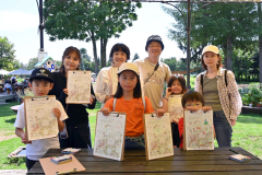 描いた絵を手にする親子連れと山本えり奈さん（後列左から２人目）と学さん（同３人目）