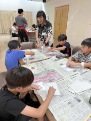 クスミさんの手ほどきを受けながら転写を体験する子どもたち
