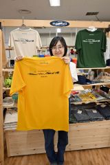 オリジナルＴシャツを手にする町観光物産協会職員