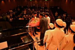駒場小１２０周年を記念したコンサート後に兵庫稲美合唱団のメンバーの椿野代表（左手前から２人目）とミマスさん（左奥から２人目）に駒場小の児童の代表二人が花束を手渡した