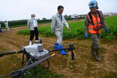 ドローンの散布で効率化された農業について中原さん(写真右)や足助組合長(同左)から説明を受ける米沢市長(中央)