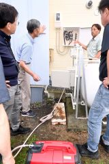 停電時に自家発電に切り替える開閉器の説明を受ける男性（左から２人目）