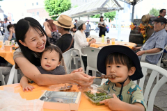 特設テントで地元グルメを味わう来場者（６日午前１０時５０分ごろ、駅北口広場・須貝拓也撮影）