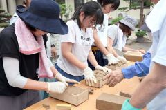 こねた粘土を木枠に詰めて形を整える参加者たち（助川かおる通信員撮影）