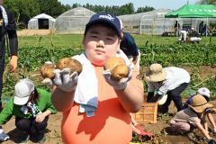 収穫したジャガイモを掲げる参加者