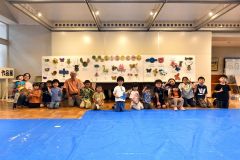 完成した「生きもの図鑑」の前に集まる堀川さんと子どもたち